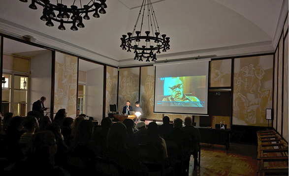 A large group of people are sitting in a dark room, watching a movie on a large screen.

Description generated by AI