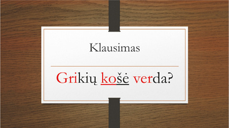A presentation slide displayed on a dark wooden background. At the top, the slide heading reads “Klausimas”. In the center, the Lithuanian target sentence “Grikių košė verda?” is shown. Stressed syllables in each word are marked in red text, and the phrase-prominent target word “košė” is underlined.
