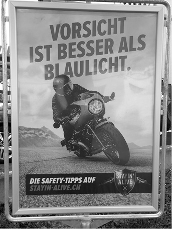 A person wearing protective gear is riding a motorcycle on a road with mountains in the background, accompanied by a German safety message about caution being better than blue lights and a website for safety tips.

Description generated by AI