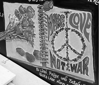 An open spiral notebook displays a drawing of a peace symbol made of flowers with the words "MAKE LOVE NOT WAR" alongside a bouquet of flowers and handwritten text below.
Description generated by AI